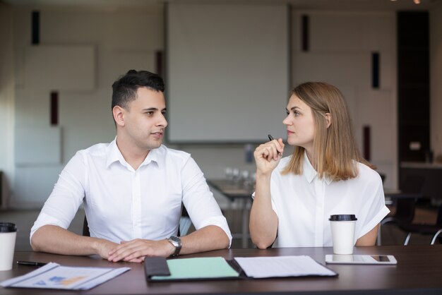 Confident businesspeople talking at meeting or seminar. 