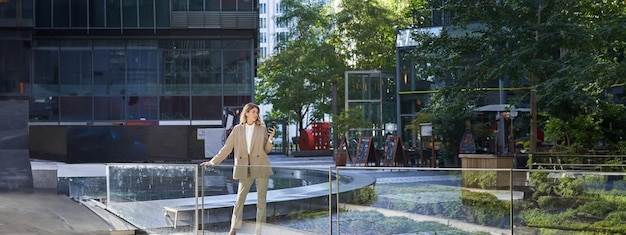 Free photo confident businesswoman in beige suit standing in power pose in city center