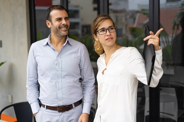 Confident businesswoman showing something to male colleague