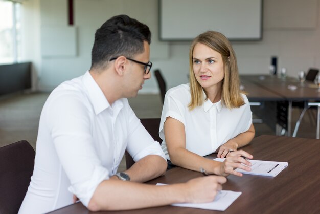 Confident businesswoman talking at meeting to male colleague. 