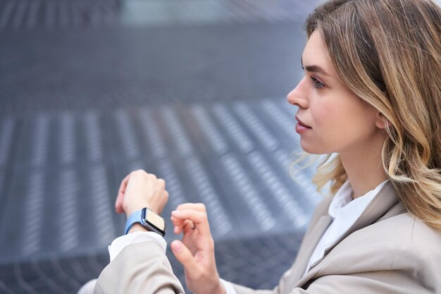 デジタル時計を持った自信に満ちたビジネスウーマンが、メッセージをチェックしたり、offi を着用した時間を会議に出席したりします。