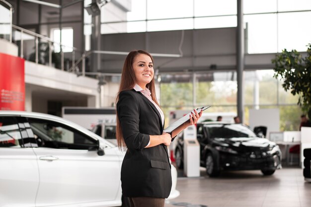 Confident car dealer holding a clipboard