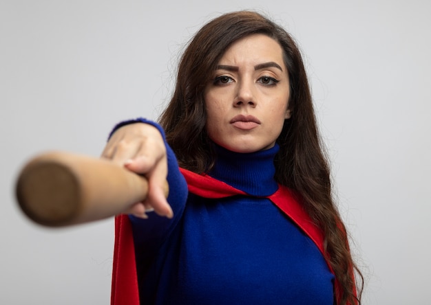 Free photo confident caucasian superhero girl with red cape holds out baseball bat on white