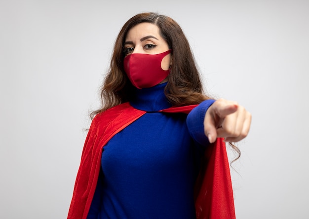 Free photo confident caucasian superhero girl with red cape wearing red protective mask