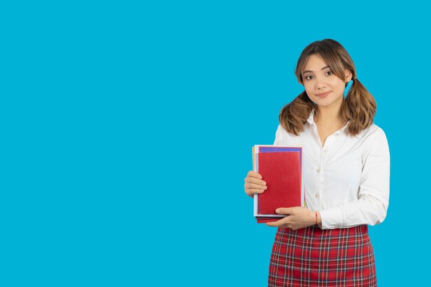 Confident college girl holding her books and looking at camera. High quality photo