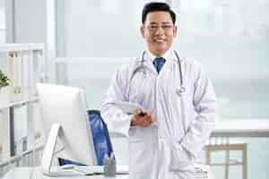 Free photo confident doctor looking at camera holding the tablet pc