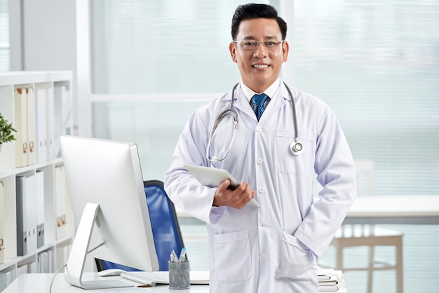 Free photo confident doctor looking at camera holding the tablet pc