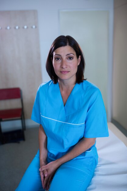 Confident doctor sitting on bed in hospital