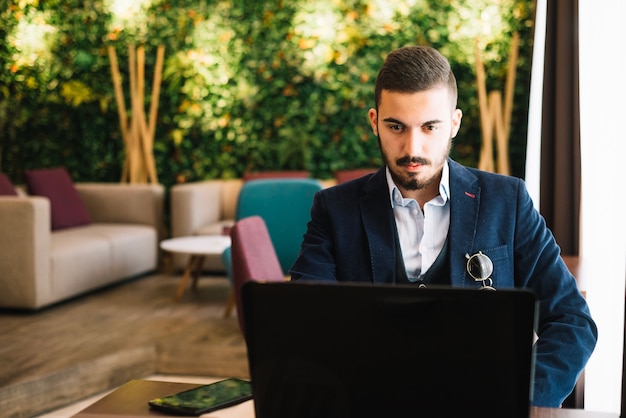 Confident entrepreneur with laptop in cafe