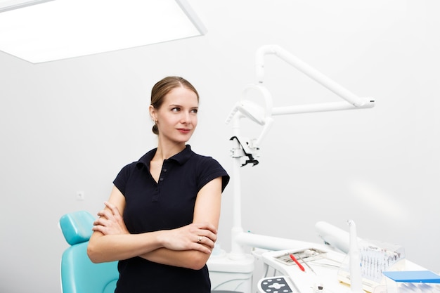 Free photo confident female dentist stands in the middle of white office