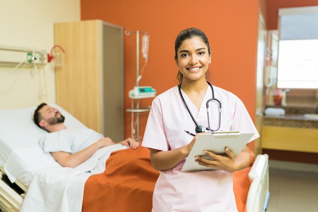 Confident female doctor with reports on clipboard standing against male patient at hospital