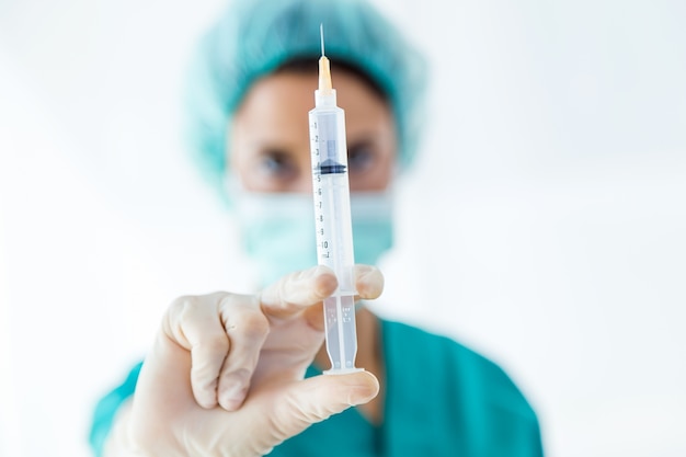 Confident female medical worker posing with a syringe in his hand and looking to the camera.