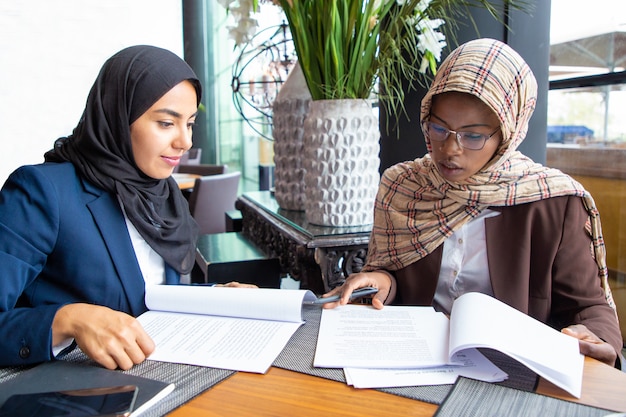 Confident female professionals checking documents