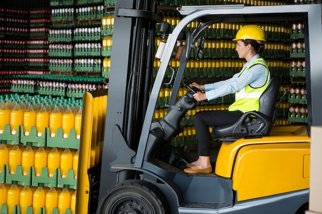 Free photo confident female worker driving forklift in warehouse