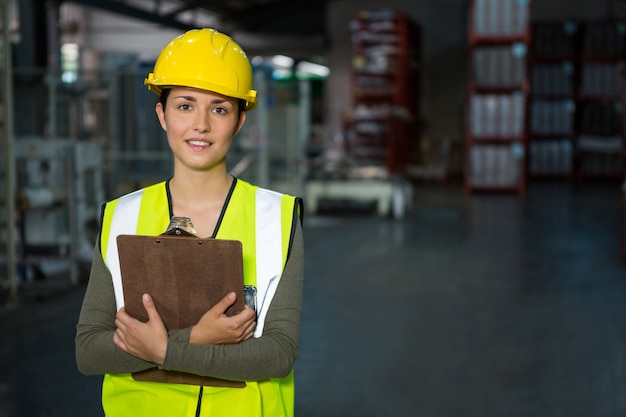 Confident female worker holding clipboard in warehouse