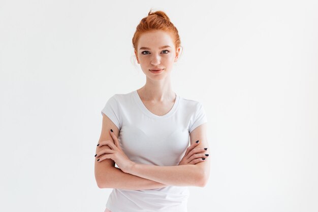 Confident ginger woman in t-shirt posing with crossed arms and looking