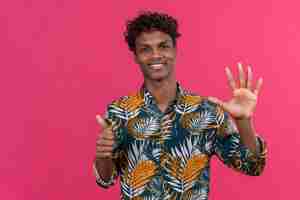 Free photo confident good-looking dark-skinned man with curly hair in leaves printed shirt showing number six with hands