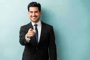 Free photo confident good looking young businessman pointing finger while standing against isolated background