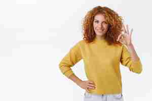 Free photo confident goodlooking assertive redhead caucasian woman with curly hair show okay sign and smiling with selfassured expression give her approval or permission satisfied with good result