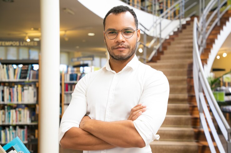 Free Photo confident guy with crossed arms standing in front of stairs