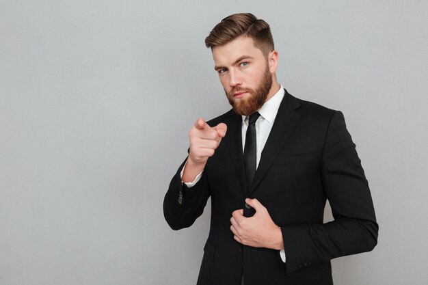Confident handsome businessman in suit pointing finger