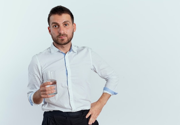 Confident handsome man holds glass of water isolated on white wall