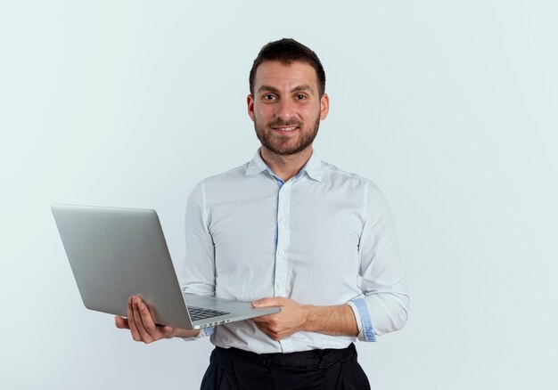 Confident handsome man holds laptop isolated on white wall