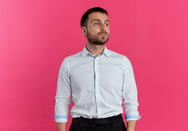 Confident handsome man looks at side isolated on pink wall