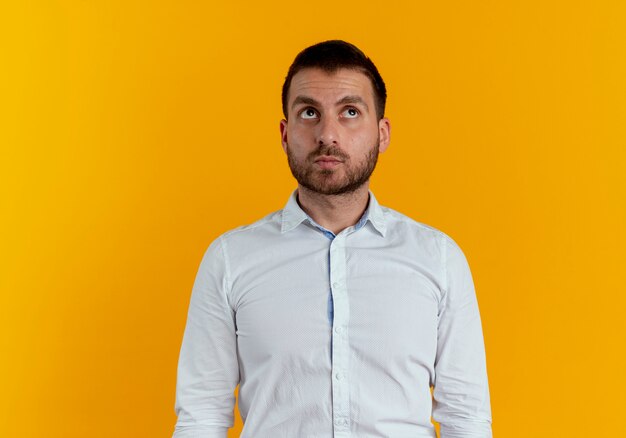 Confident handsome man looks up isolated on orange wall