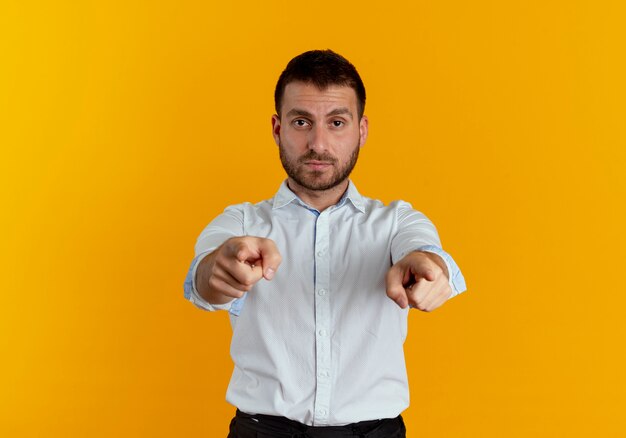 Confident handsome man points with two hands isolated on orange wall