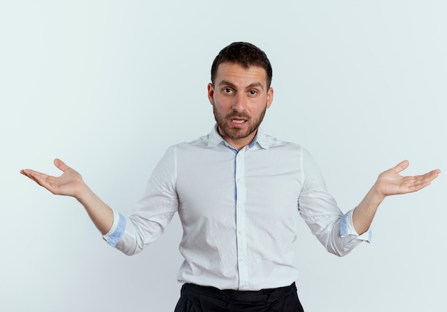 Confident handsome man stands with open hands isolated on white wall