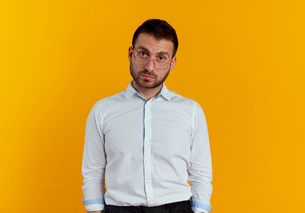 Confident handsome man with optical glasses looks isolated on orange wall