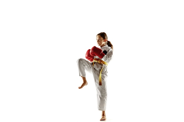 Бесплатное фото Уверенный юноша в кимоно, практикует рукопашный бой, боевые искусства. молодой женский боец с тренировкой желтого пояса на белой стене. концепция здорового образа жизни, спорта, действий.