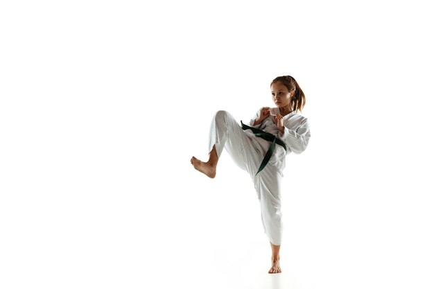 Уверенный в себе юниор в кимоно, практикующий рукопашный бой