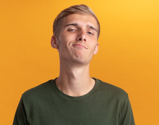 Confident looking at front young handsome guy wearing green shirt isolated on yellow wall