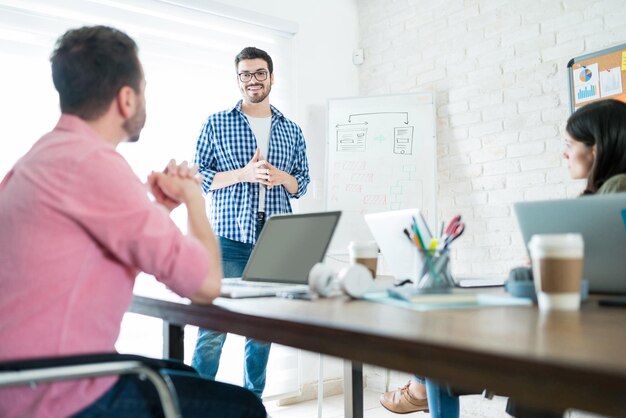 Confident male entrepreneur gives presentation to colleagues while briefing in meeting at workplace