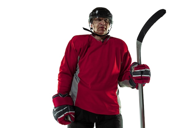 Confident. Male hockey player with the stick on ice court and white background. Sportsman wearing equipment and helmet practicing. Concept of sport, healthy lifestyle, motion, movement, action.