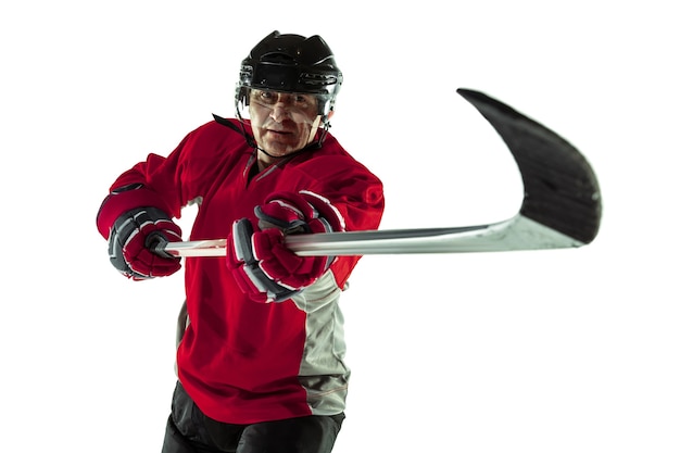 Confident. Male hockey player with the stick on ice court and white wall. Sportsman wearing equipment and helmet practicing. Concept of sport, healthy lifestyle, motion, movement, action.