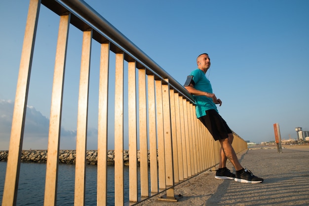 Confident male jogger resting leaning on bridge