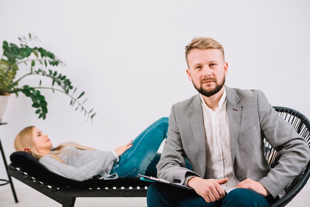 Confident male psychologist sitting on chair in front of her female patient