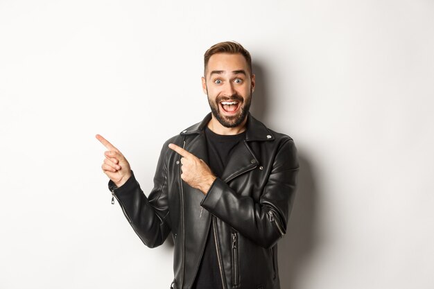 Уверенный мужчина в черной кожаной куртке, указывая пальцами влево на промо-предложение