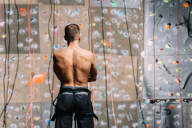 Confident man looking at climbing wall