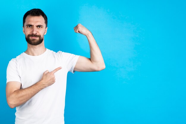 Confident man pointing at bicep