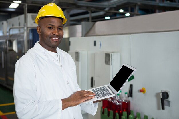 Confident man using laptop in juice factory