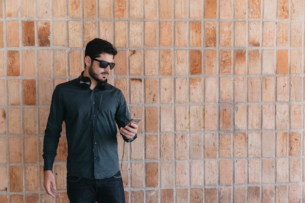 Confident man using phone with headphones