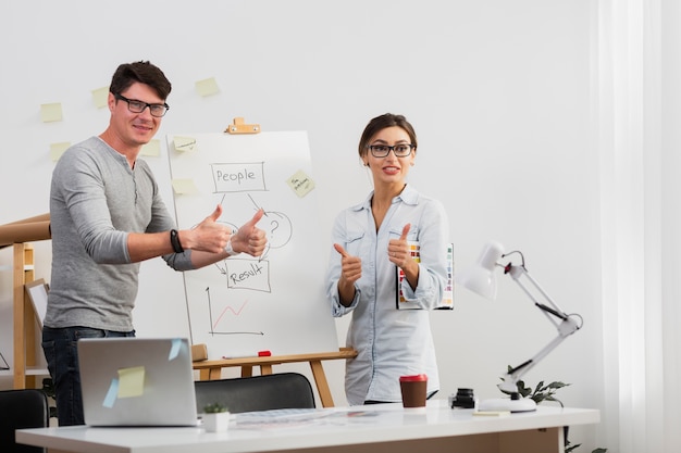 Confident man and woman showing ok sign next to a diagram