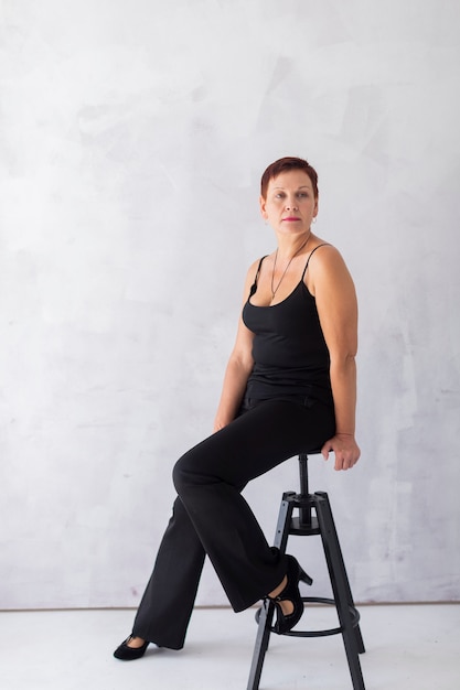 Confident mature woman sitting on a stool