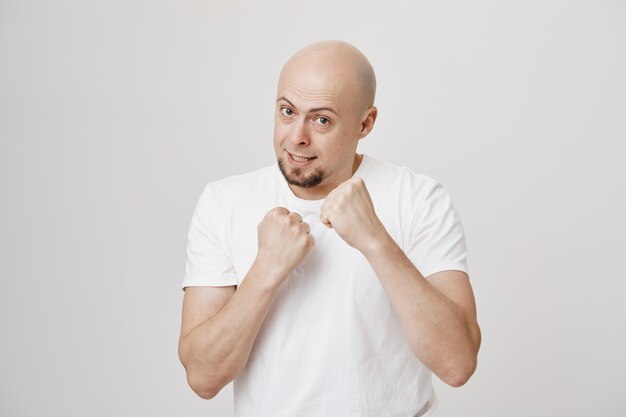 Confident middle-aged bald guy ready fight, clench fists