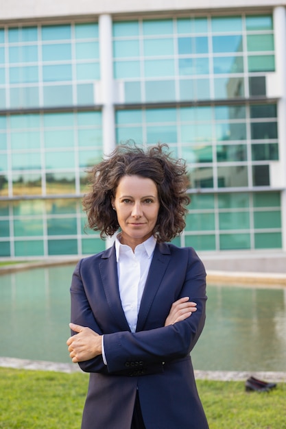 Free photo confident middle aged businesswoman posing near office building