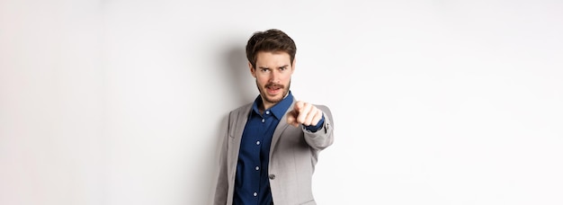 Free photo confident and motivated businessman in suit need you pointing finger at camera with encouraging face